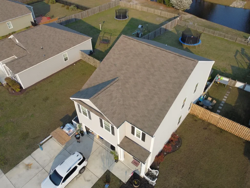 Aerial view of a two-story house with a light-colored roof and white walls